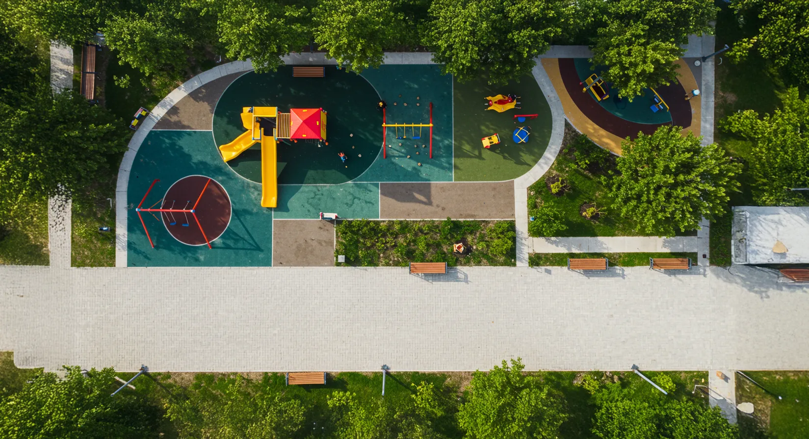 Vista cenital de una plaza de juegos con veredas hechas con adoquines unistone Firmex